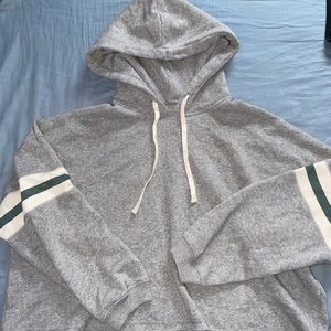cropped grey sweatshirt with green and white stripes on the arms.